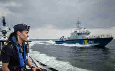 Kvinnlig kustbevakare på fartyg med KBV 312 i bakgrunden
