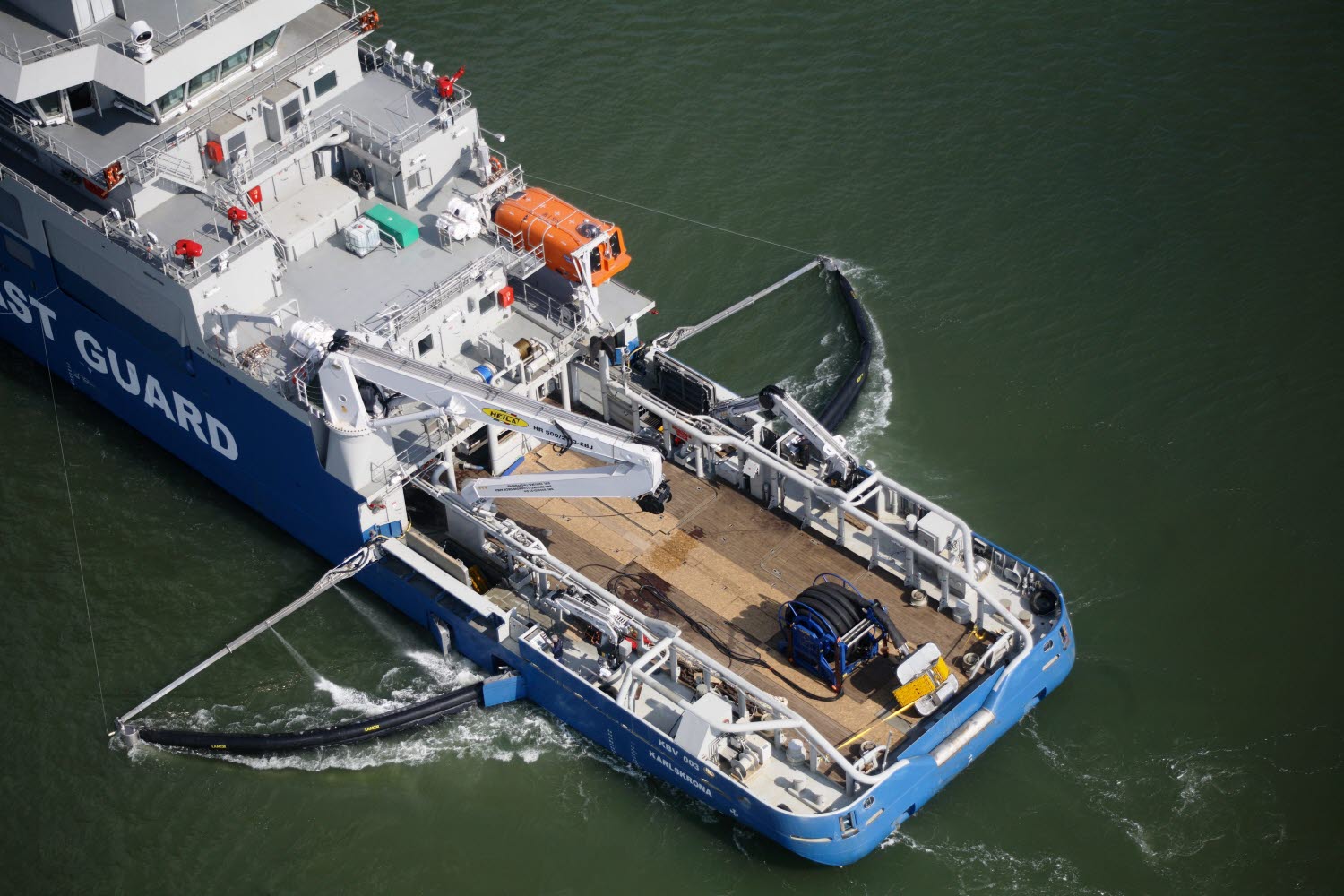 Kombinationsfartyg med utfällda sveparmar för oljeupptagning