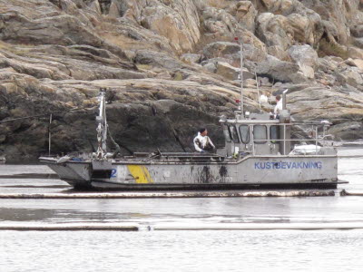 Arbetsbåt bekämpar olja nära strand